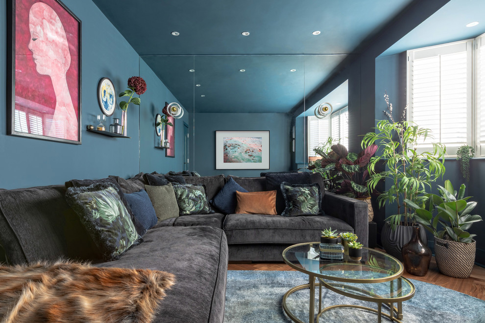 На фото: гостиная комната в современном стиле с синими стенами, темным паркетным полом и коричневым полом