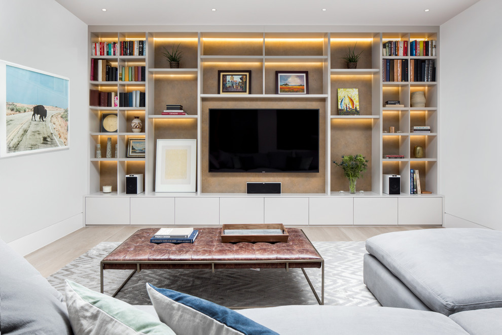Cette image montre une très grande salle de séjour design avec un mur blanc, une bibliothèque ou un coin lecture, parquet clair, aucune cheminée, un téléviseur encastré et un sol beige.