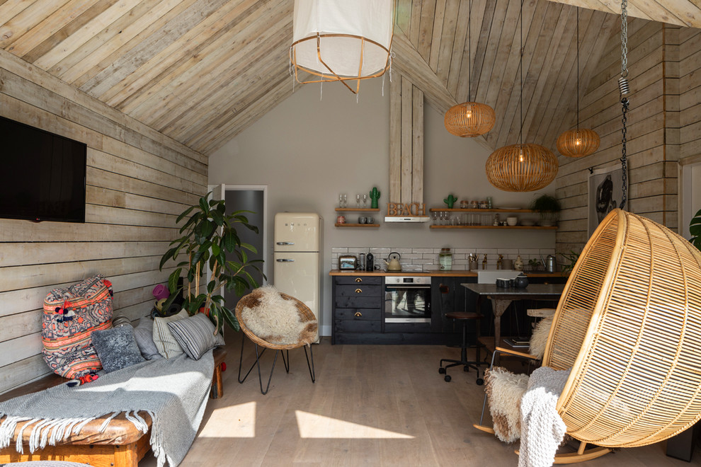 Diseño de sala de estar abierta costera de tamaño medio con paredes grises, suelo de madera clara, televisor colgado en la pared y suelo gris