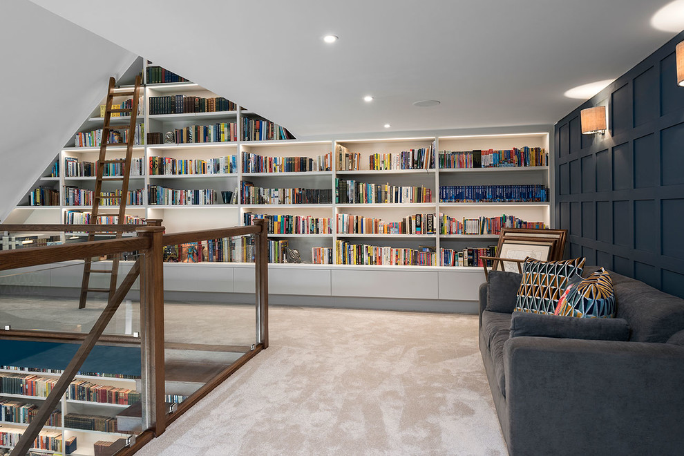 Cette image montre une grande salle de séjour mansardée ou avec mezzanine design avec une bibliothèque ou un coin lecture, un mur bleu, moquette, un téléviseur fixé au mur et un sol beige.