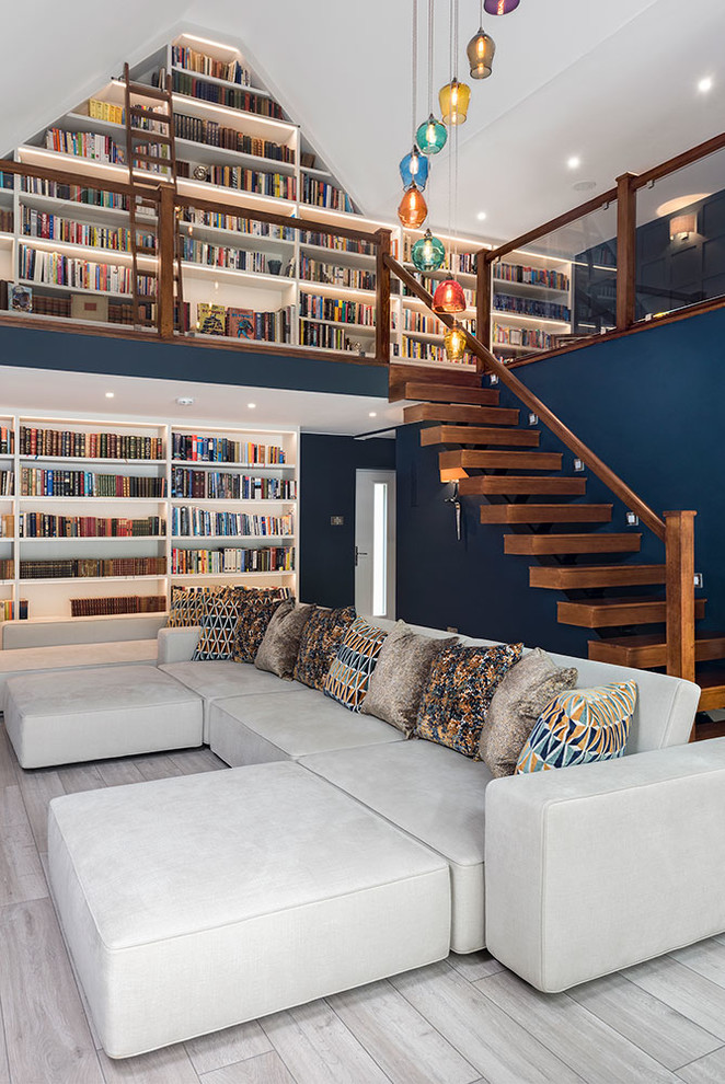 Foto på ett mellanstort funkis allrum, med ett bibliotek, blå väggar och grått golv