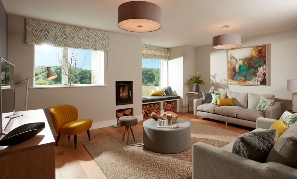 Mittelgroßes Modernes Wohnzimmer mit grauer Wandfarbe, braunem Holzboden, Kaminofen, Kaminumrandung aus Metall und freistehendem TV in Sonstige