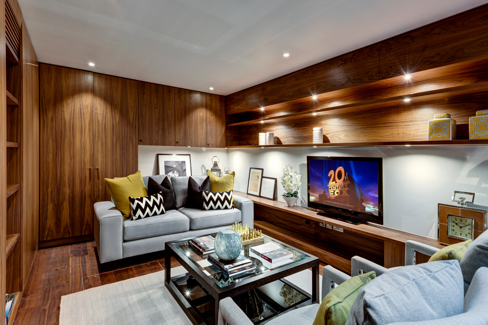Idée de décoration pour une salle de séjour design fermée avec un mur blanc et un sol en bois brun.