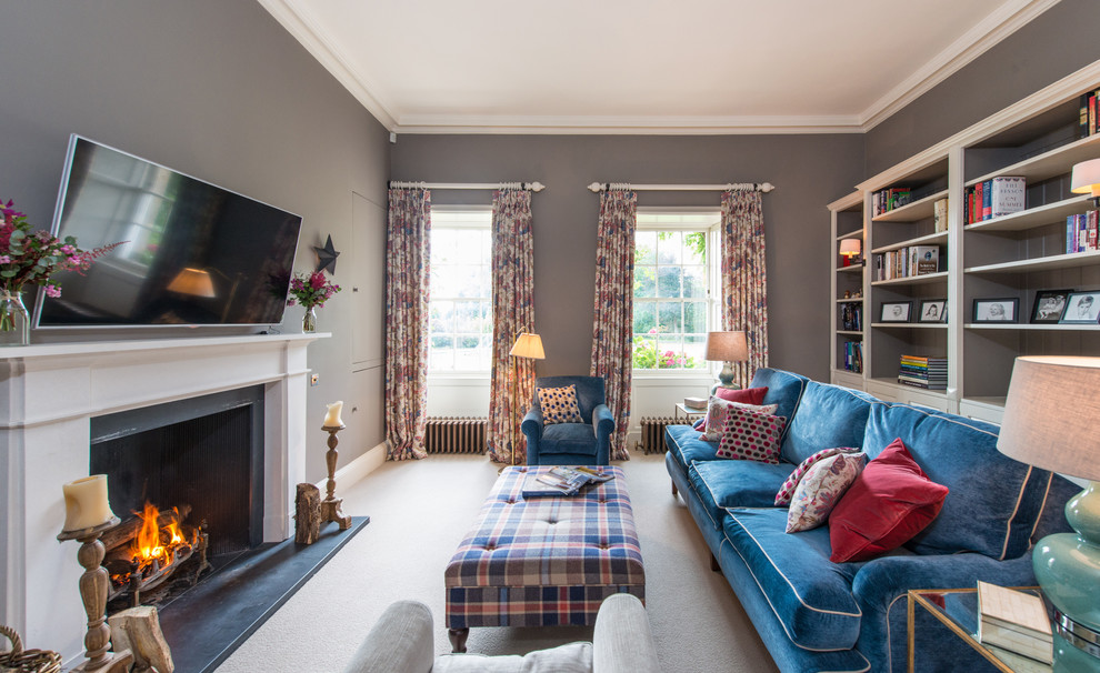 Foto de sala de estar clásica con paredes grises, moqueta, todas las chimeneas, televisor colgado en la pared y marco de chimenea de piedra