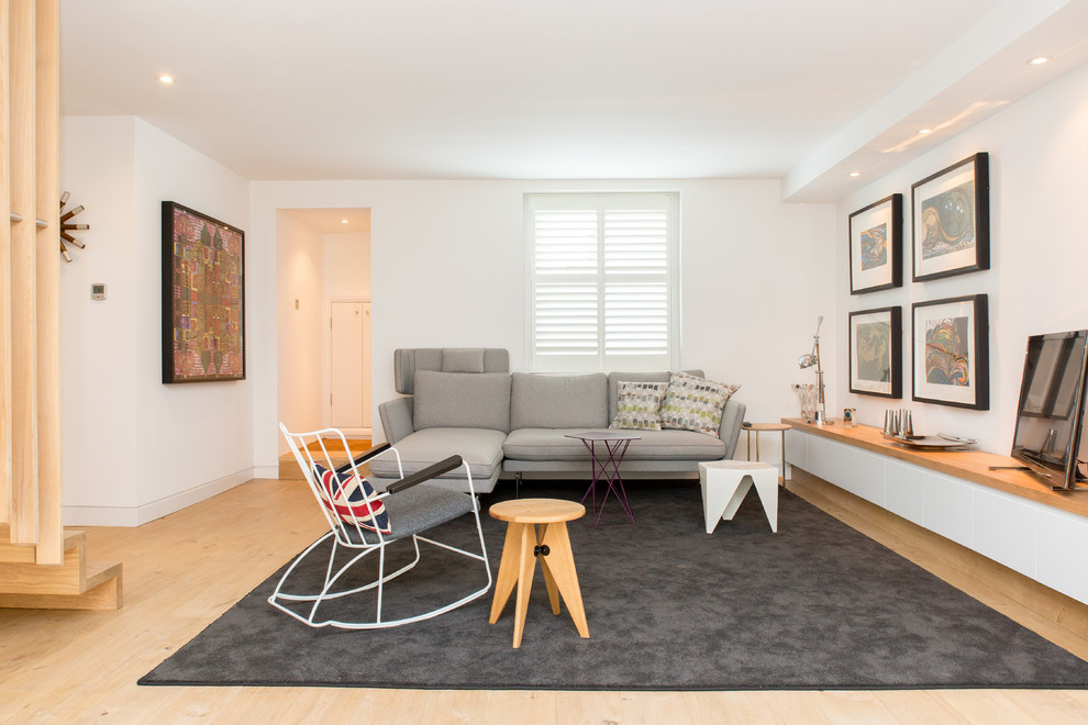 Mittelgroßes Skandinavisches Wohnzimmer ohne Kamin mit weißer Wandfarbe, hellem Holzboden und freistehendem TV in London