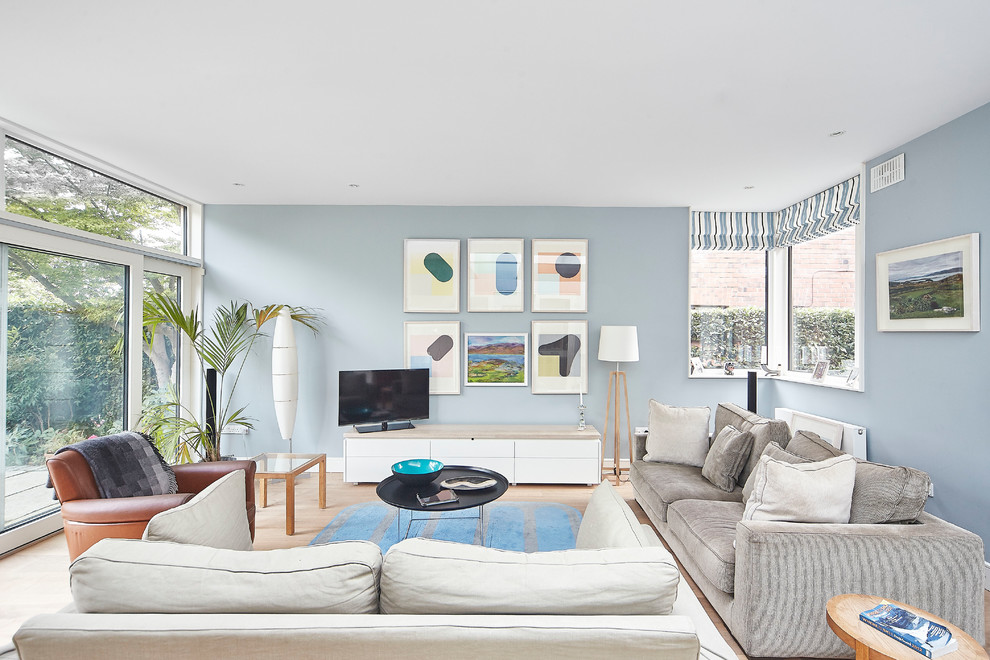 Diseño de sala de estar cerrada costera de tamaño medio con paredes azules, suelo de madera clara, televisor independiente y suelo beige