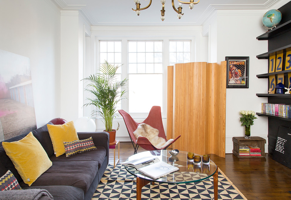 Modelo de sala de estar bohemia sin chimenea con paredes blancas, suelo de madera oscura y suelo marrón