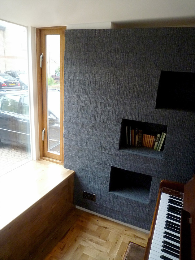 Imagen de sala de estar con rincón musical cerrada actual con paredes negras y suelo de madera clara