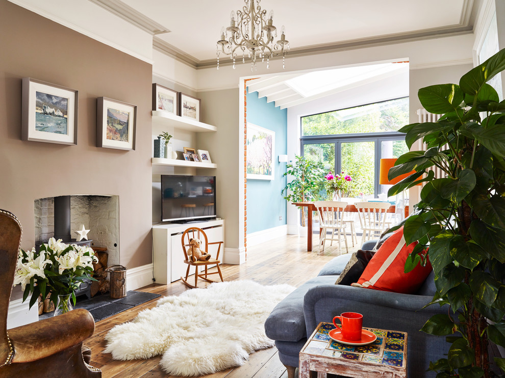 Foto de sala de estar abierta tradicional renovada con paredes beige, suelo de madera en tonos medios, estufa de leña, marco de chimenea de ladrillo y suelo marrón