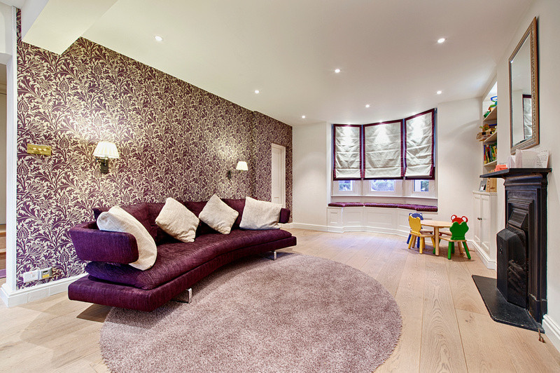 Photo of a medium sized classic open plan games room in London with a game room, purple walls, light hardwood flooring, a standard fireplace, a metal fireplace surround and a freestanding tv.