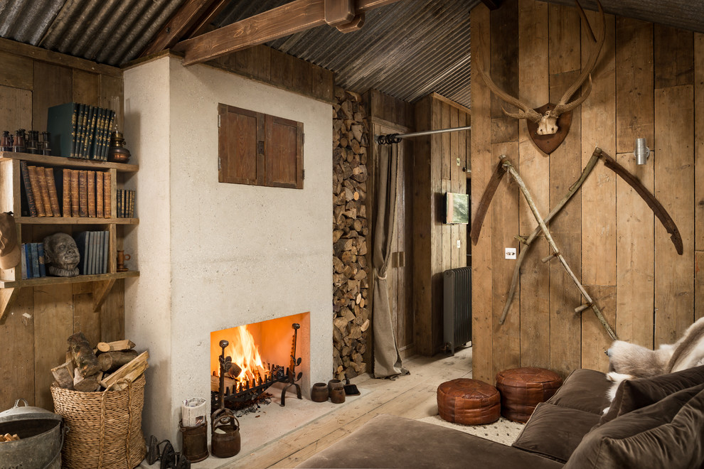 Photo of a rustic games room in Cornwall with a reading nook, light hardwood flooring, a standard fireplace, a concealed tv and a concrete fireplace surround.