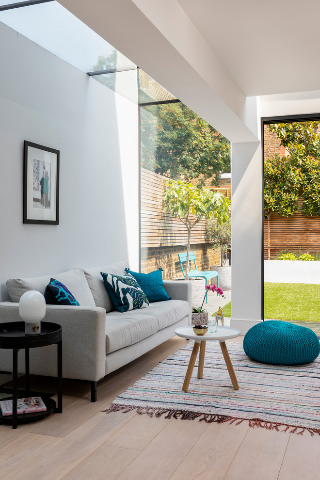 Modelo de sala de estar abierta contemporánea grande sin chimenea y televisor con paredes grises, suelo de madera clara y suelo beige