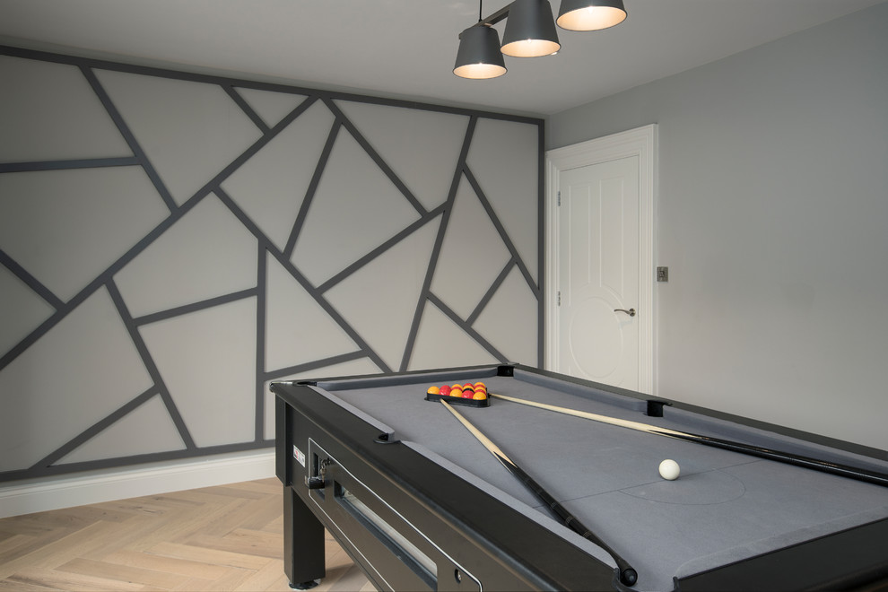 Diseño de sala de juegos en casa cerrada contemporánea de tamaño medio con paredes grises, suelo de madera en tonos medios y suelo gris