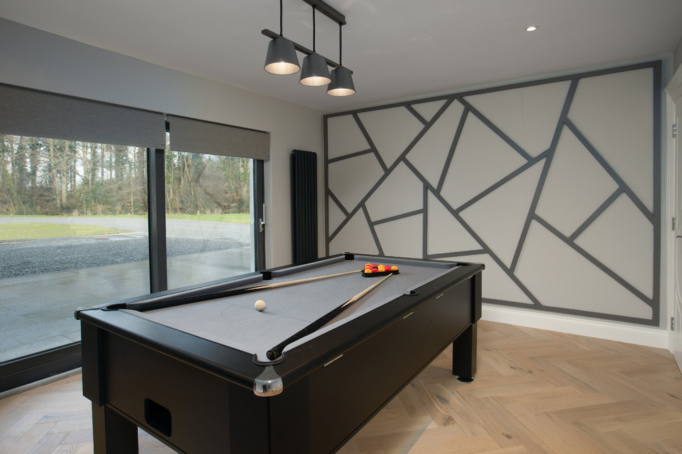 Modelo de sala de juegos en casa cerrada actual de tamaño medio con paredes grises, suelo de madera en tonos medios, suelo gris y madera