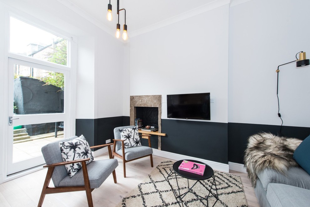Идея дизайна: гостиная комната в скандинавском стиле с разноцветными стенами, светлым паркетным полом и телевизором на стене