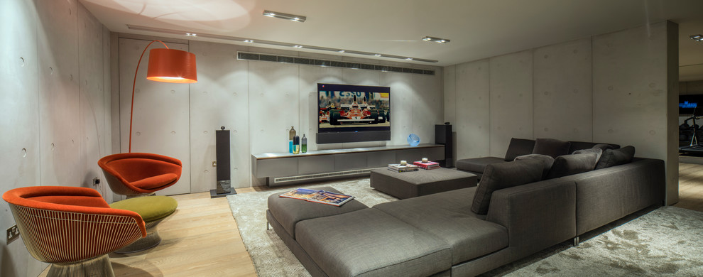 Стильный дизайн: большая открытая комната для игр в классическом стиле с серыми стенами, светлым паркетным полом и телевизором на стене без камина - последний тренд