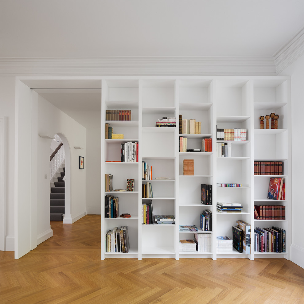 Modelo de sala de estar con biblioteca moderna con paredes blancas y suelo de madera en tonos medios