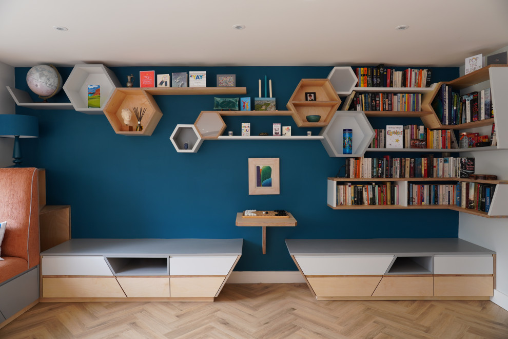 Réalisation d'une salle de séjour nordique de taille moyenne et ouverte avec une bibliothèque ou un coin lecture, un mur bleu, un sol en bois brun et un sol marron.