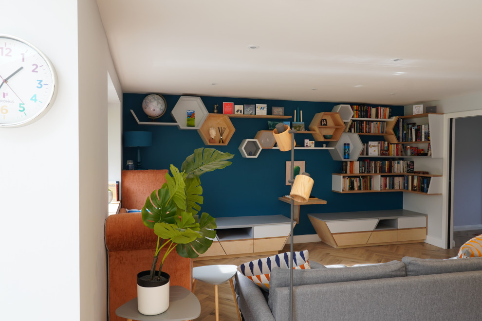 Cette photo montre une salle de séjour scandinave de taille moyenne et ouverte avec une bibliothèque ou un coin lecture, un mur bleu, un sol en bois brun et un sol marron.