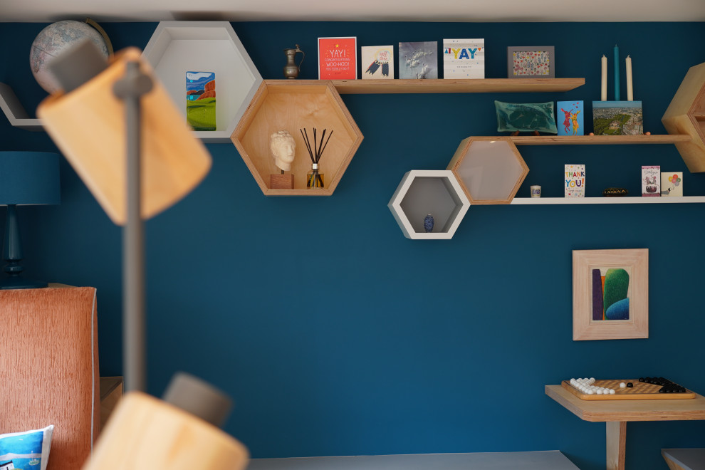 Ejemplo de sala de estar con biblioteca abierta escandinava de tamaño medio con paredes azules, suelo de madera en tonos medios y suelo marrón