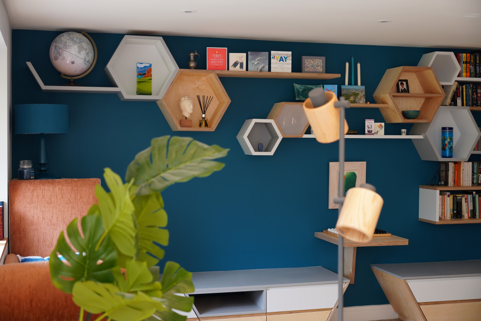 Idee per un soggiorno scandinavo di medie dimensioni e aperto con libreria, pareti blu, pavimento in legno massello medio e pavimento marrone