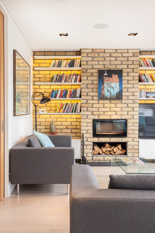 Ejemplo de sala de estar contemporánea con paredes blancas, suelo de madera clara, pared multimedia, marco de chimenea de metal y chimenea lineal