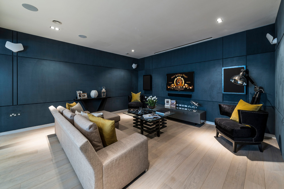 На фото: изолированная гостиная комната среднего размера в стиле неоклассика (современная классика) с синими стенами, телевизором на стене, бежевым полом и светлым паркетным полом