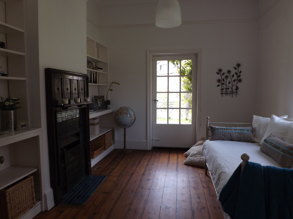 Diseño de sala de estar cerrada tradicional pequeña sin televisor con paredes blancas, suelo de madera en tonos medios, todas las chimeneas y marco de chimenea de madera