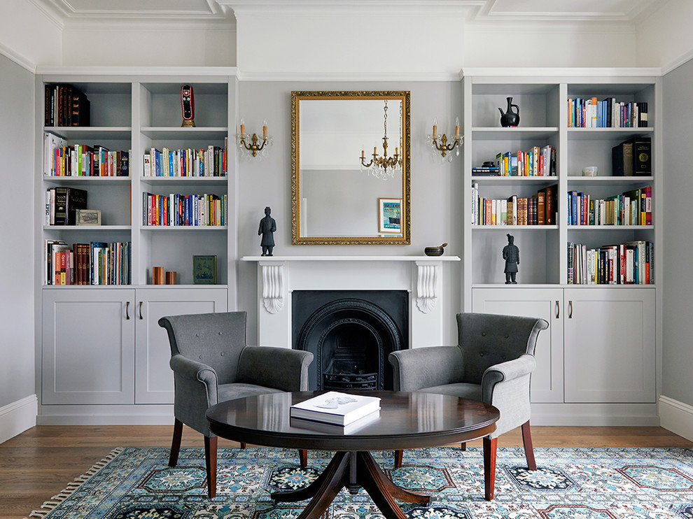 Diseño de sala de estar con biblioteca clásica renovada de tamaño medio sin televisor con suelo de madera en tonos medios y todas las chimeneas
