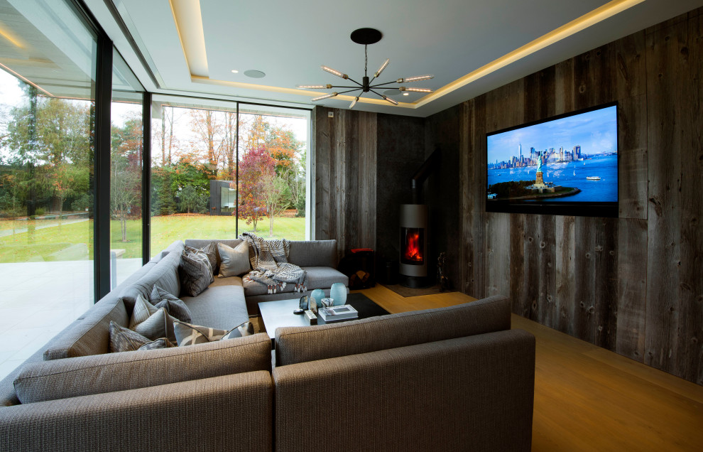 На фото: изолированная комната для игр среднего размера в современном стиле с телевизором на стене, коричневыми стенами, подвесным камином, фасадом камина из металла и коричневым полом