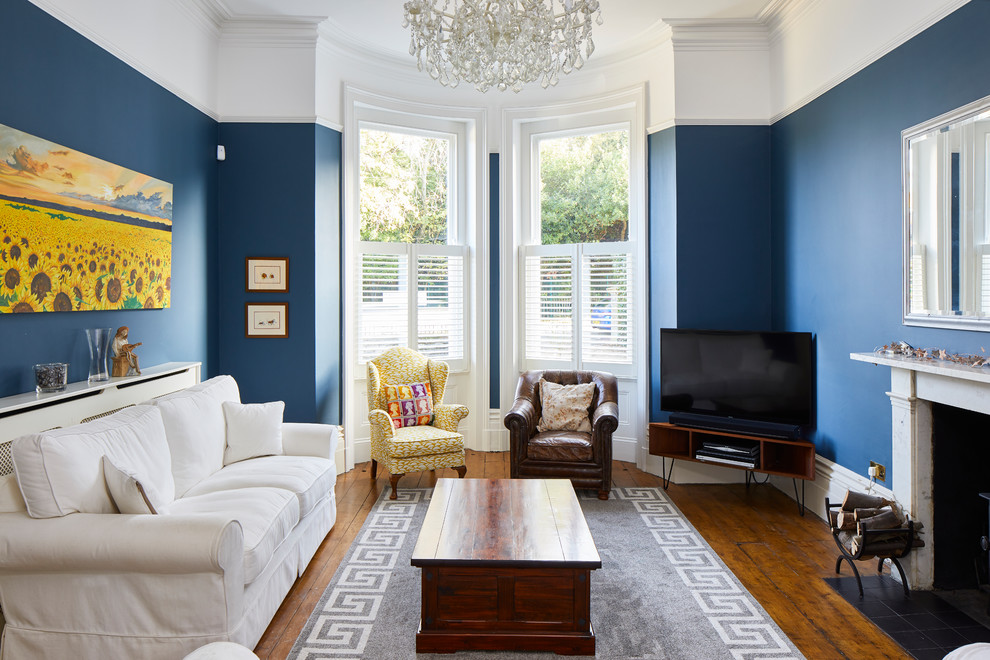 Immagine di un soggiorno tradizionale con pareti blu, pavimento in legno massello medio, camino classico, TV autoportante e pavimento marrone