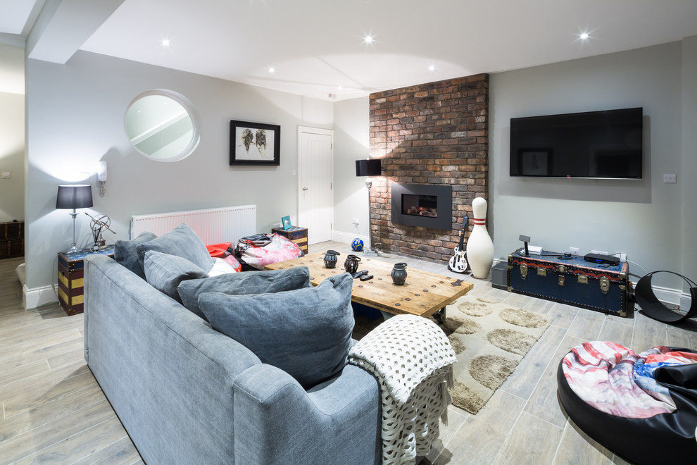 Modelo de sala de estar contemporánea de tamaño medio con paredes grises, suelo de madera clara, televisor colgado en la pared, suelo beige y todas las chimeneas