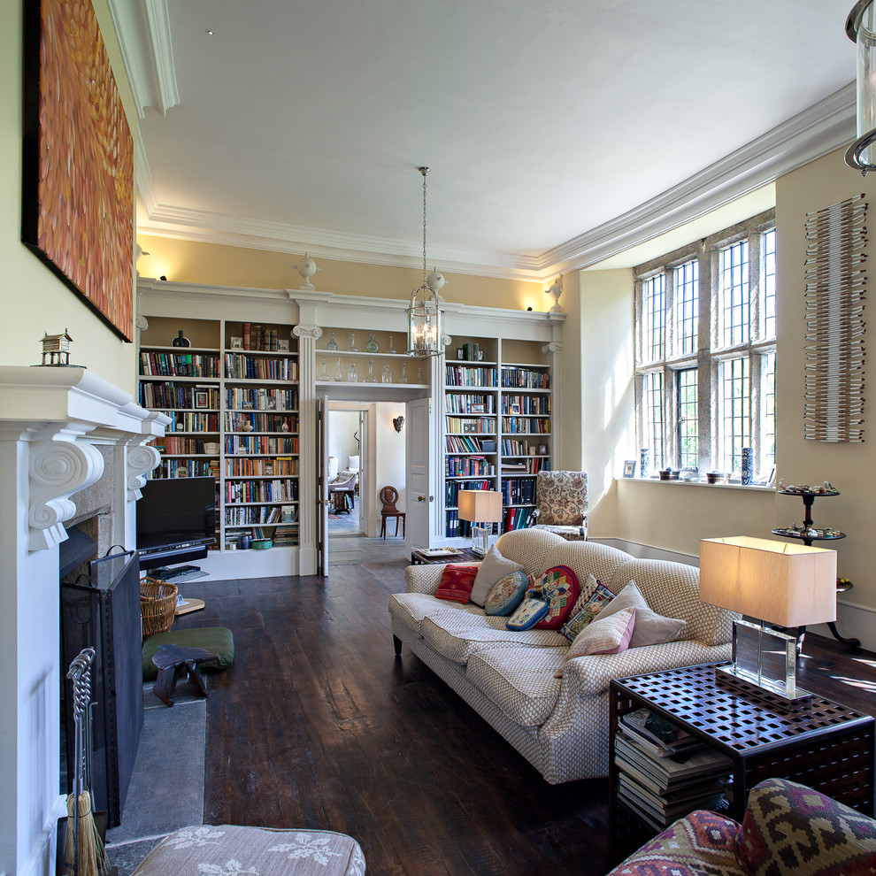 Modelo de sala de estar con biblioteca cerrada clásica con paredes amarillas, suelo de madera oscura, televisor en una esquina y todas las chimeneas