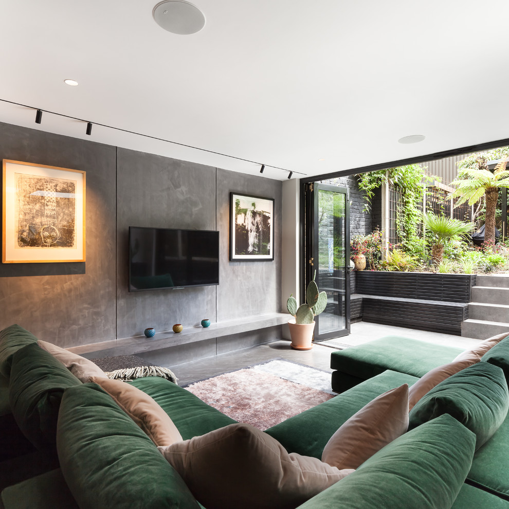 Cette image montre une salle de séjour design de taille moyenne et ouverte avec un mur gris, sol en béton ciré, un téléviseur fixé au mur et un sol gris.