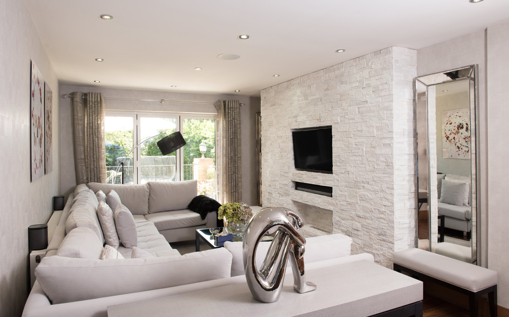 Diseño de sala de estar tradicional renovada pequeña con paredes grises, pared multimedia, chimenea lineal y marco de chimenea de piedra