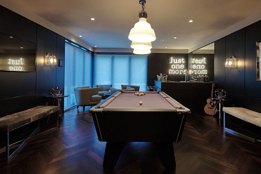 Cette photo montre une salle de séjour tendance de taille moyenne et fermée avec salle de jeu, un mur noir, un sol en bois brun et un téléviseur encastré.