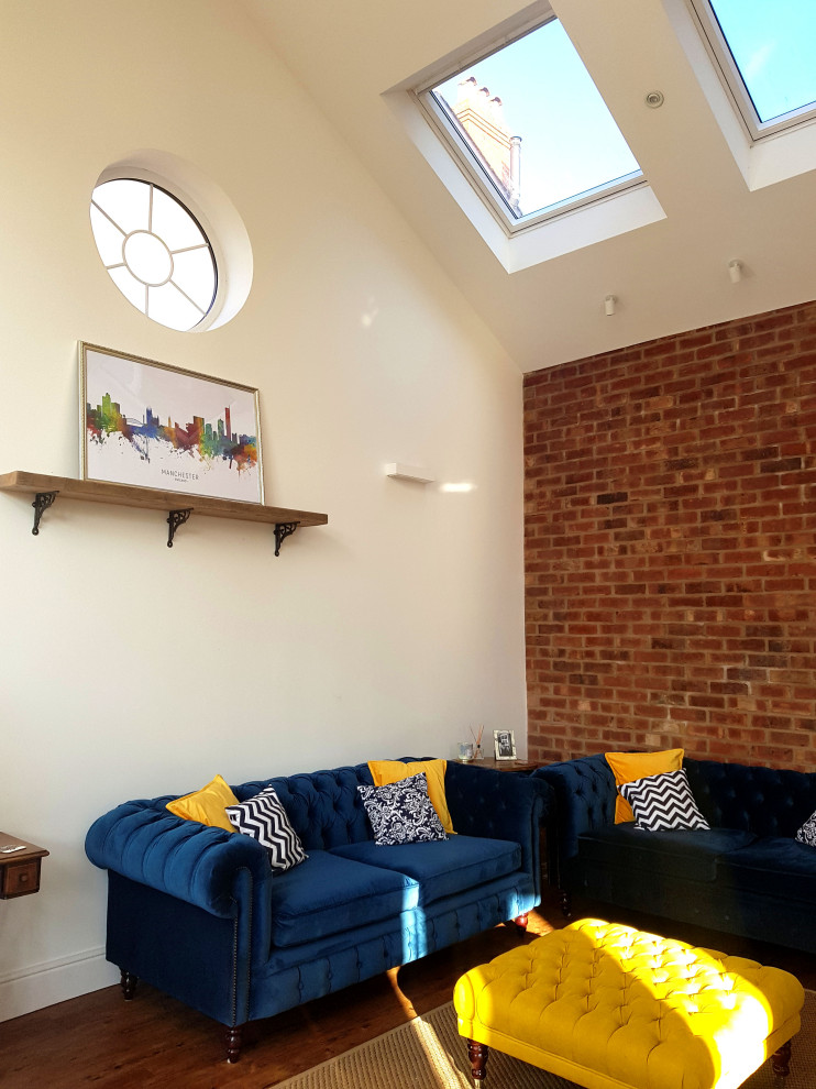 This is an example of a medium sized traditional open plan games room in Manchester with a reading nook, white walls, medium hardwood flooring, no fireplace, a wall mounted tv, brown floors, a vaulted ceiling and brick walls.