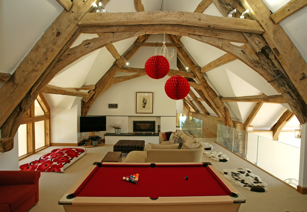 This is an example of a large country mezzanine games room in Dorset with white walls, carpet, a standard fireplace, a corner tv and beige floors.