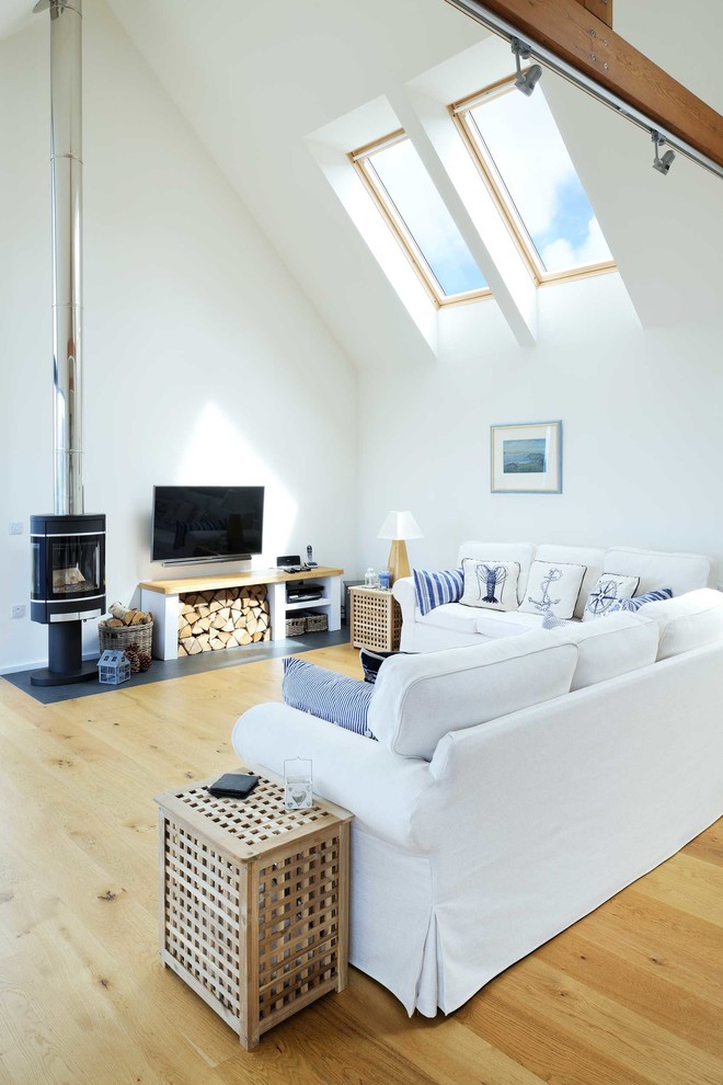 This is an example of a medium sized nautical open plan games room in Other with white walls, laminate floors, a wood burning stove, a wall mounted tv and a metal fireplace surround.