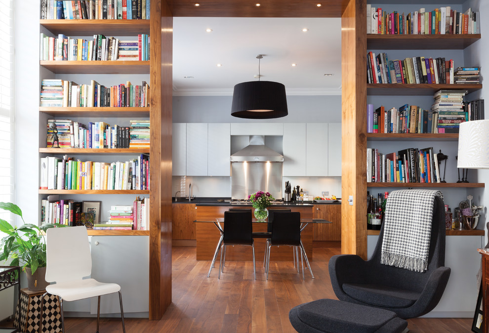 Imagen de sala de estar con biblioteca contemporánea de tamaño medio con paredes grises, suelo de madera en tonos medios y suelo marrón