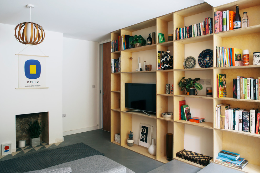 Пример оригинального дизайна: открытая гостиная комната в скандинавском стиле с с книжными шкафами и полками, белыми стенами, бетонным полом, стандартным камином, фасадом камина из бетона, отдельно стоящим телевизором и серым полом