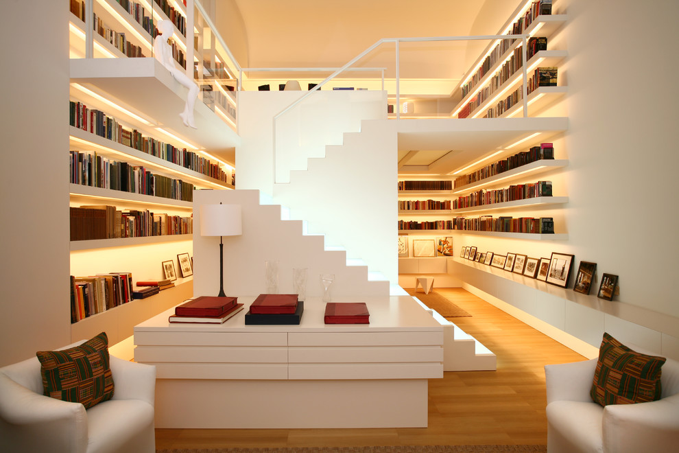 Imagen de sala de estar con biblioteca abierta actual con paredes blancas y suelo de madera en tonos medios