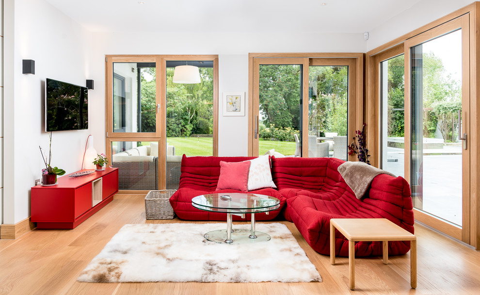 Example of a transitional light wood floor and beige floor family room design in Cambridgeshire with white walls, a wall-mounted tv and no fireplace