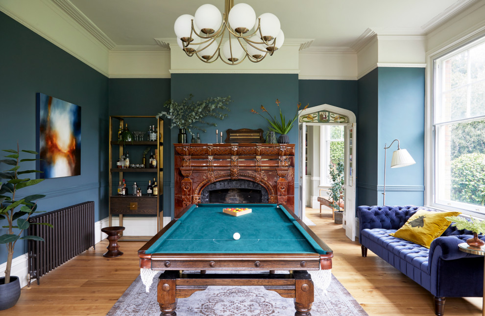 This is an example of a classic games room in London with blue walls, medium hardwood flooring, brown floors and a dado rail.
