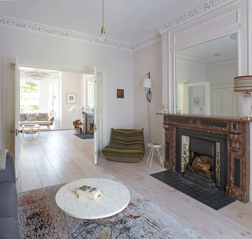 Cette image montre une salle de séjour traditionnelle avec un mur blanc, parquet clair, une cheminée standard et un manteau de cheminée en pierre.