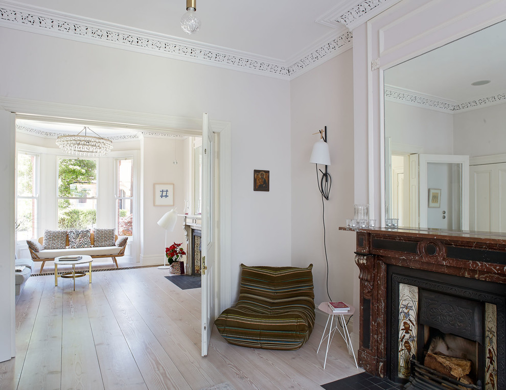 Klassisches Wohnzimmer mit weißer Wandfarbe, hellem Holzboden, Kamin und Kaminumrandung aus Stein in Dublin