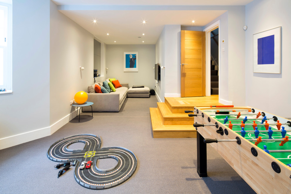 Imagen de sala de juegos en casa actual de tamaño medio con paredes grises, moqueta, televisor colgado en la pared y suelo gris