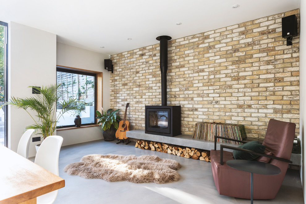 Foto di un soggiorno scandinavo aperto con sala della musica, pareti bianche, pavimento in cemento, stufa a legna e pavimento grigio