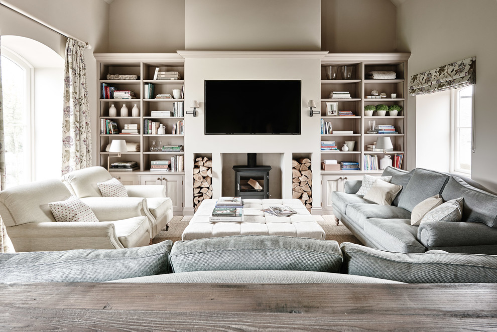 Foto di un soggiorno classico con libreria, pareti beige, stufa a legna e TV a parete
