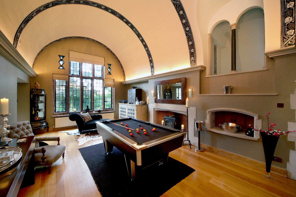 Classic open plan games room in London with green walls, a standard fireplace, a game room and medium hardwood flooring.